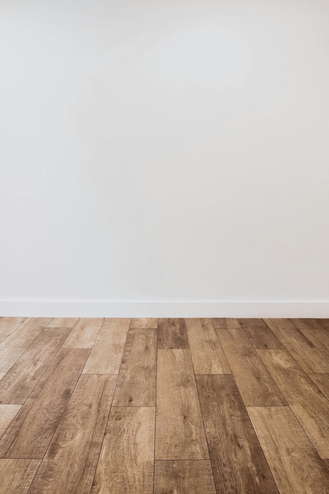 Close-up of finished hardwood plank flooring against a white wall